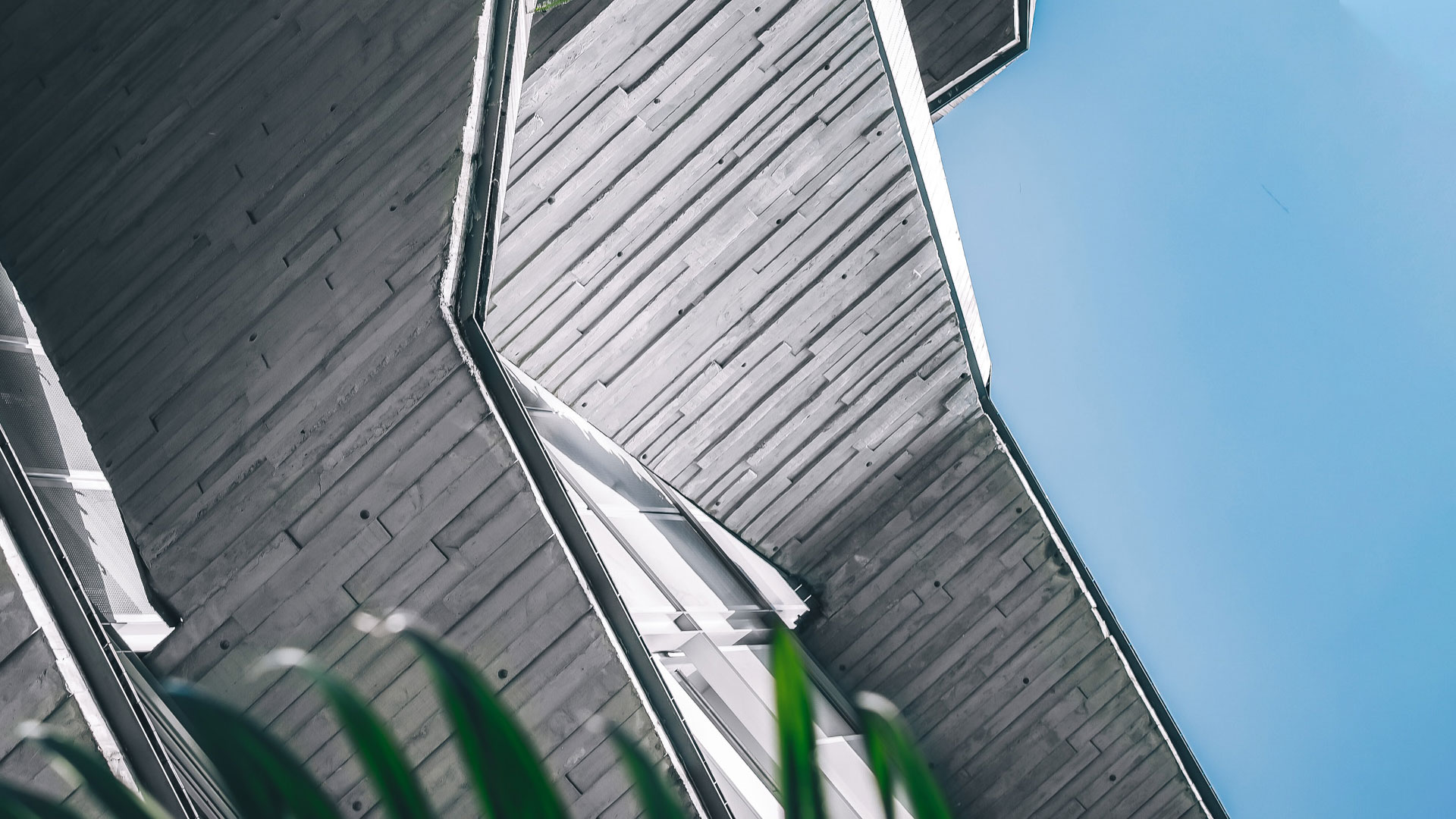 Close-up of The Oliv's sloping origami-like roofline against a blue sky